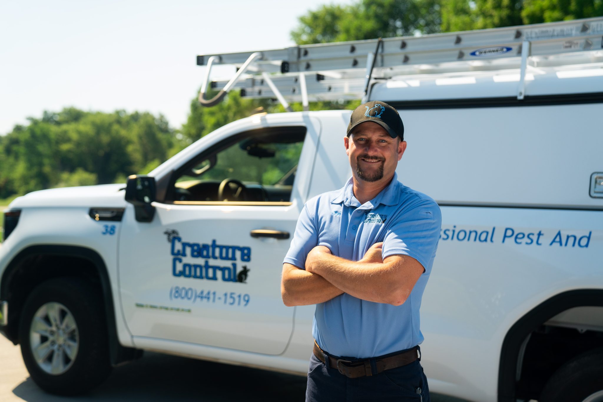 A Creature Control pest control technician standing in front of a company truck.