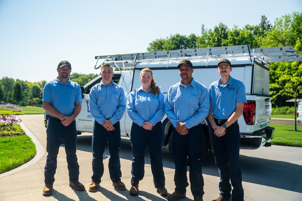 A team photo in front of a Creature Control truck in a customers driveway.